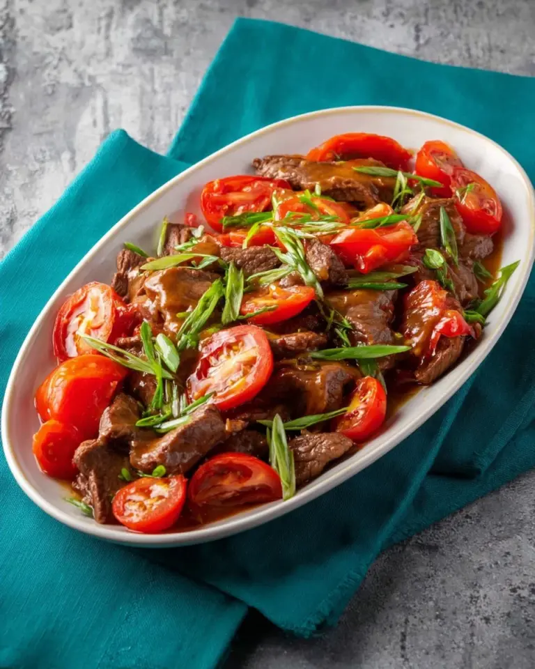Beef stir fry with tomatoes served over jasmine rice on a plate