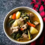 A bowl of Thai Pork Rib Soup with herbs and spices, showcasing succulent pork ribs.