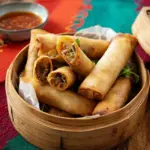 Plate of ultimate crispy veggie spring rolls served with dipping sauce.